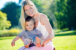 Barefoot toddler sitting in lap of smiling woman