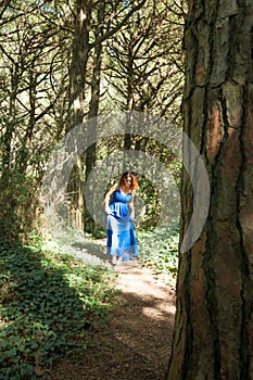 Barefoot woman dressed in blue walking alone through forest