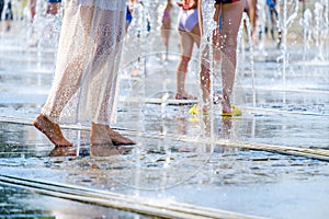 A barefoot woman escapes the heat in splashes of water in a city fountain.