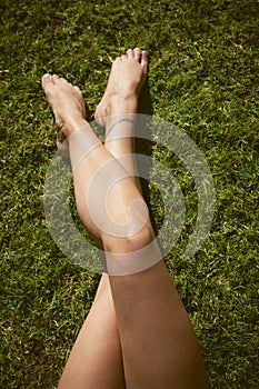 Barefoot woman legs on grass