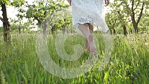 Barefoot woman`s legs walking on green grass