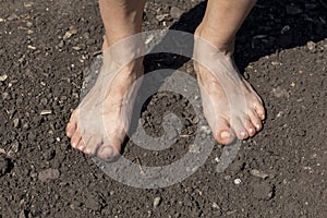 Barefoot woman stands on the raw soil photo