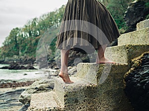 Barefoot woman walking up steps in nature