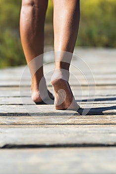 Barefoot woman walking on a wooden pier. Concept of nudism and naturism. Female people legs in clos eup. Summer holiday vacation photo