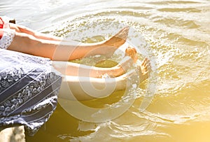 Barefoot women washing feet in river. Beautiful girls near lake. Friends enjoying holiday. Rustic summer flat lay. Wooden bridge.