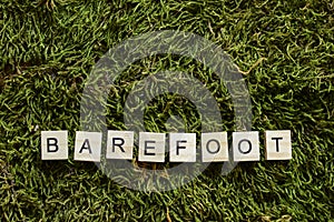 Barefoot written with wooden letters cubed shape on the green grass
