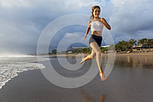Sporty girl running by beach along sea surf