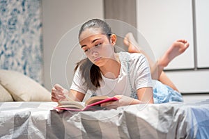 Barefoot young teenage girl lying on her bed reading photo