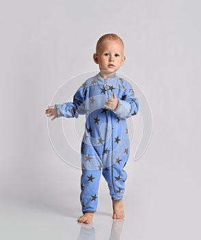 Barefooted baby boy in blue fleece jumpsuit with stars runs