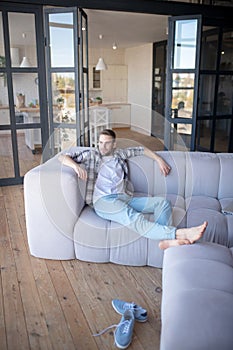 Barefooted man chilling on sofa in the living room