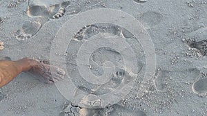 Barefooted man legs walk on white sandy ocean beach with long waves on resort.