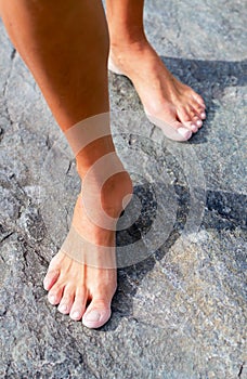 Barefooted woman`s leg on hot rock