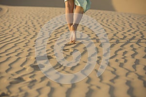 Barefooted woman walks in the sand of desert