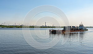 A barge carries cargo along the Sheksna River against the backdrop of the Cherepovets Metallurgical Plant