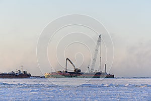 Barge with crane. Dredger working at sea. Sunset in Arctic sea. Construction Marine offshore works. Dam building, crane, barge,