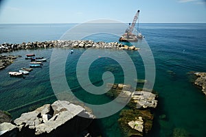 Barge with crane for dredging the seabed at the port of Riomaggiore, Cinque Terre, stock photo