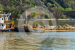 A barge, flat-bottomed boat, pushed by tugboat along the river to transport gravel and grit