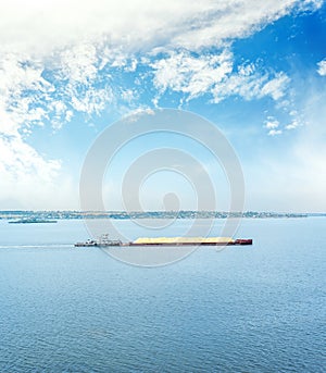 barge loaded with sand on the river. blue sky with clouds over big river