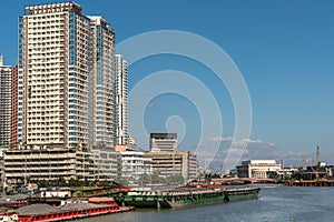 Barges and skyscrapers along Paisg River in Manila Philippines