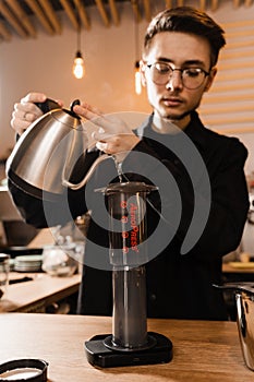 Barista is brewing aeropress coffee in cafe. Process of aeropress alternative method brewing coffee. Pouring hot water