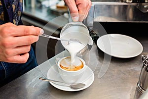 Barista in cafe or coffee bar preparing cappuccino