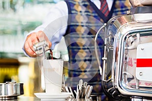 Barista in cafe pouring espresso shot in latte macchiato photo