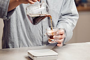 Barista Carefully Pours Brewed V60 Coffee Into Transparent Glass photo