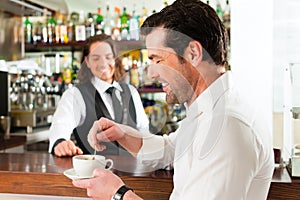 Barista with client in his cafe or coffeeshop photo