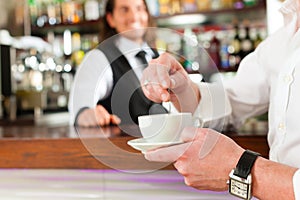 Barista with client in his cafe or coffeeshop photo
