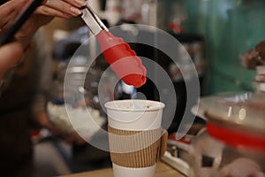 The barista in the coffee shop decorates the coffee with marshmallows against the background of the coffee machine. Selectiv focus