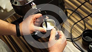 Barista frothing milk in a milk jug with a cappuccinatore of a coffee machine