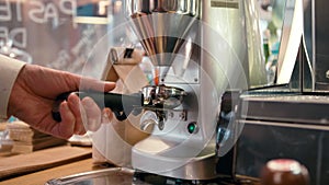 Barista is grinding coffee beans with grinder machine in the cafe, bar or shop