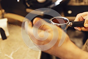 Barista grinding freshly roasted coffee beans from a professional modern electric grinder into a powder