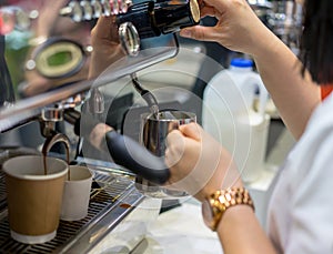 Barista hand adjusting level of steam pressure for milk frothing
