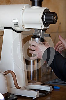 Barista hands grinding coffee with white mahlkonig grinder in coffee shop, closeup