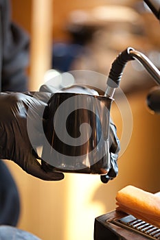 Barista hands steaming milk for coffee in modern espresso machine