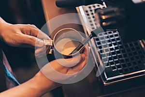 Barista heats milk steam for making lattes at coffee shop