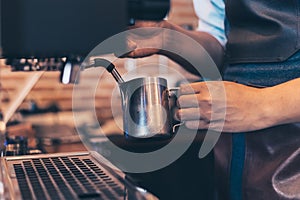 Barista heats milk steam for making lattes at coffee shop
