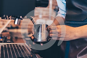 Barista heats milk steam for making lattes at coffee shop