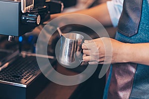 Barista heats milk steam for making lattes at coffee shop