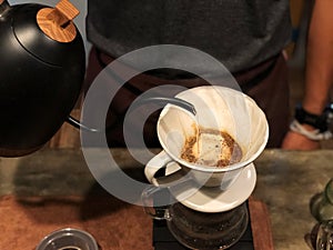 Barista holding Black kettle and Dripping water on ground coffee