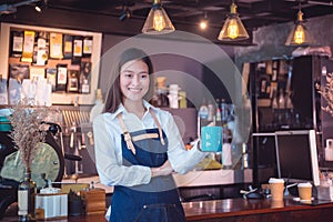 Barista holding coffee cup and smiles in her caf