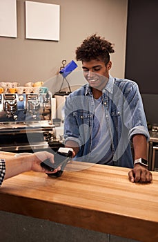 Barista holding reader and man paying by smartphone