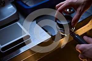 Barista holding tamper and portafilter with coffee for making coffee espresso