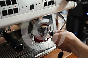 Barista inserting portafilter into coffee machine indoors