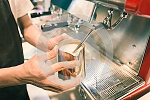 Barista made foam milk by coffee machine with vintage tone.