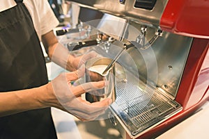 Barista made foam milk by coffee machine with vintage tone.