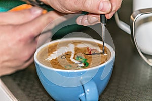 Barista making an art from the fresh milk in the little ceramic cup of the delicious hot espresso