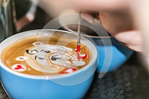 Barista making an art from the fresh milk in the little ceramic cup of the delicious hot espresso