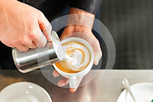 Barista making cappuccino in his coffeeshop photo